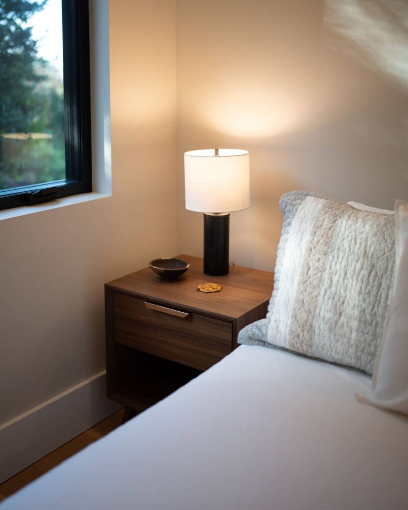 Bedside table in a dark wood grain next to bed