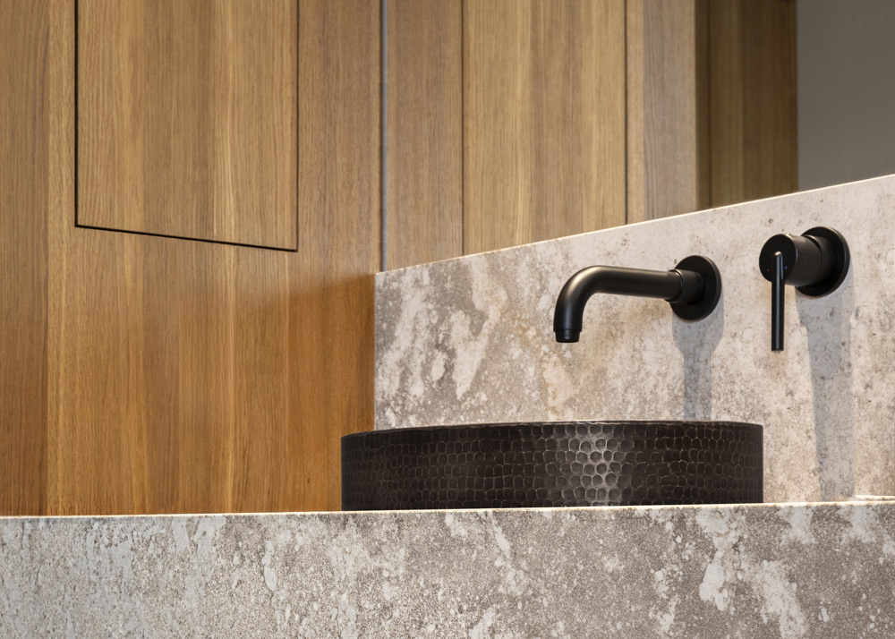 close up of textured black sink with wood and mirror background