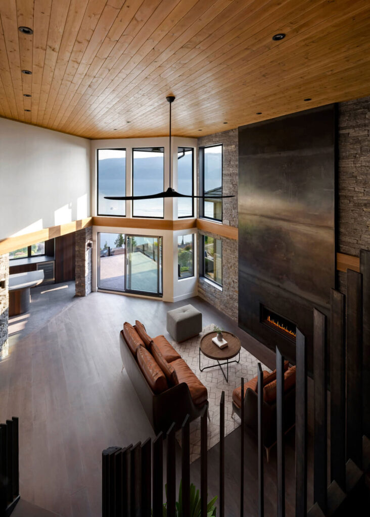 view from top of staircase showing raw metal fireplace and light coming in through windows