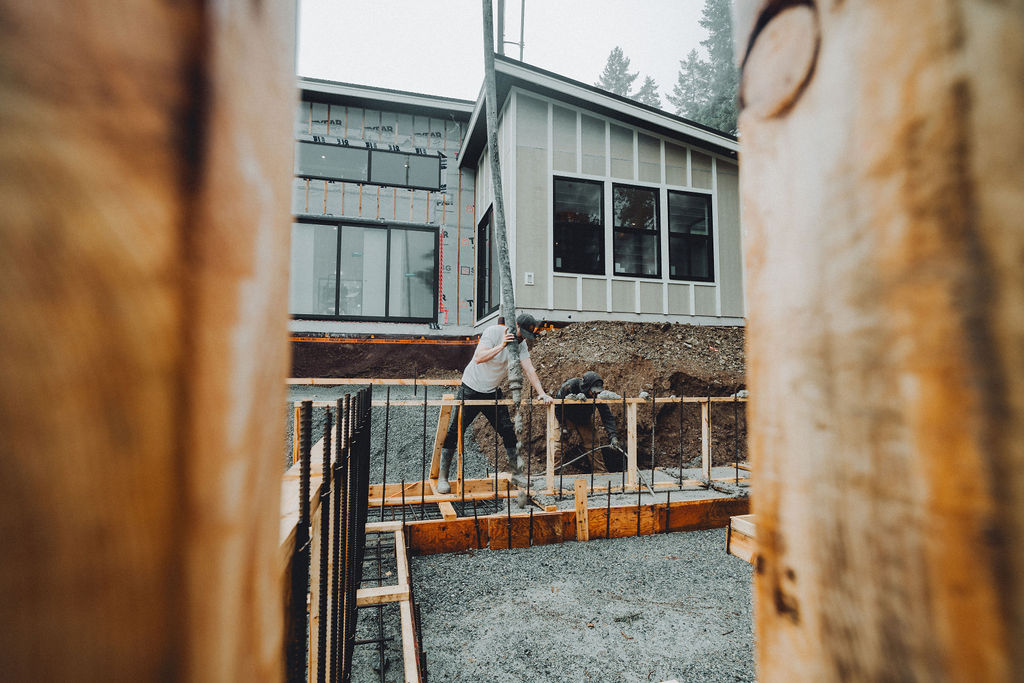 pouring concrete to form the deck and patio area around a modern home