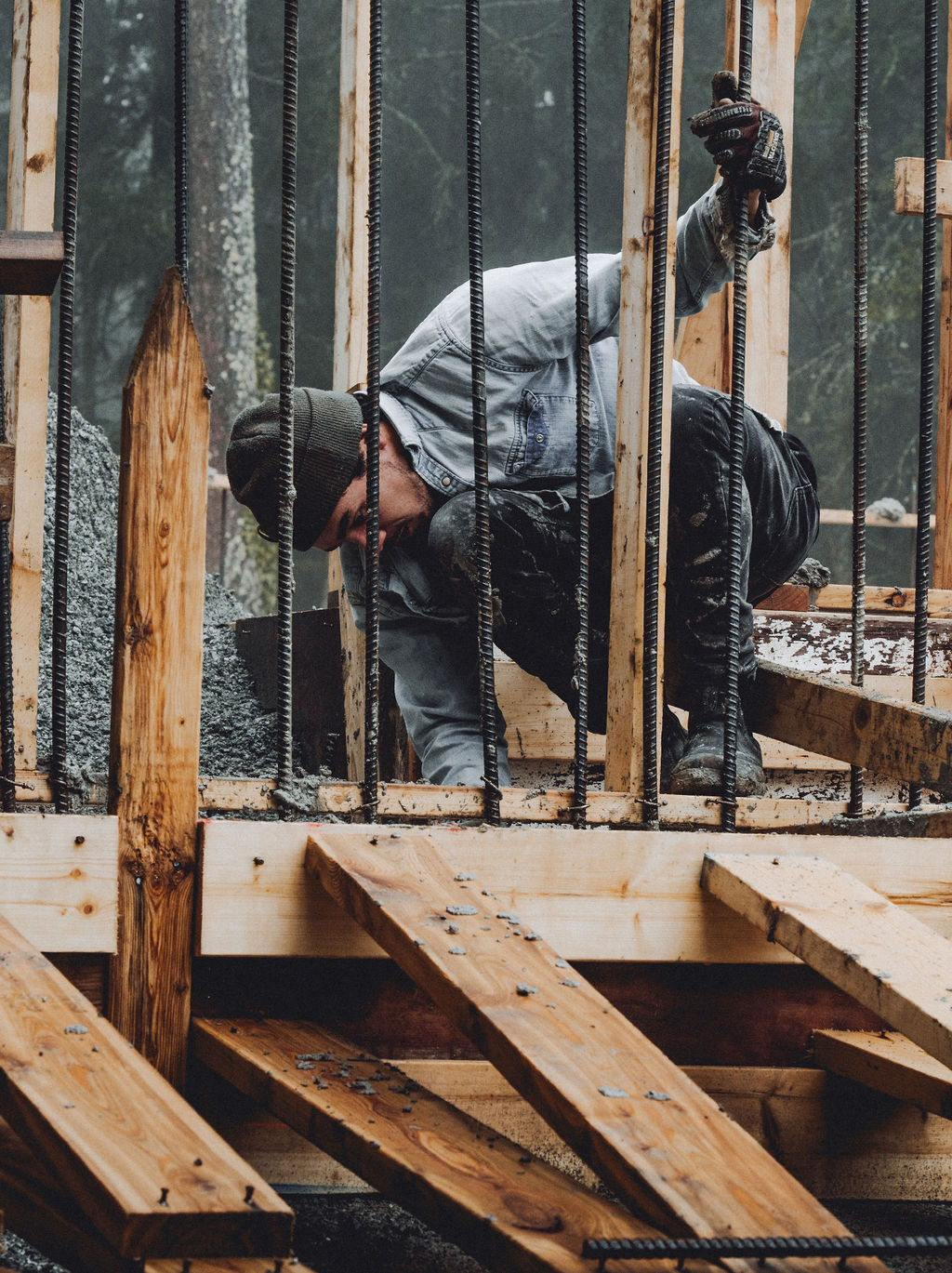 man fitting rebar and wood into cement